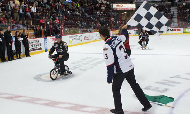 Helio Castroneves waves the checkered flag at Windsor Spitfires game