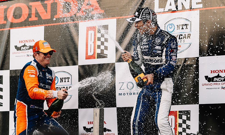 Scott Dixon sprays champagne on Takuma Sato