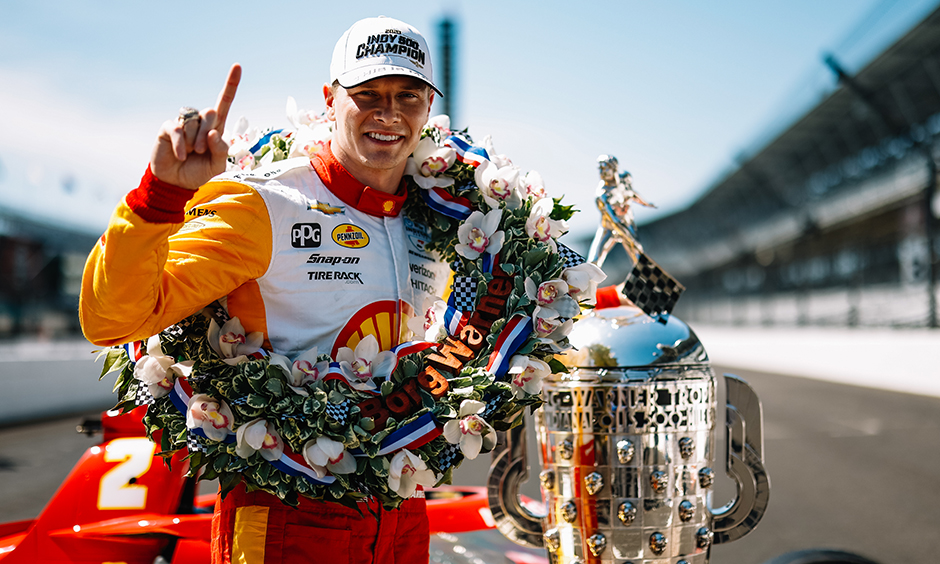 Josef Newgarden pictured with the Borg-Warner Trophy and the winner's wreath on the frontstretch of Indianapolis Motor Speedway during the winner's photoshoot.